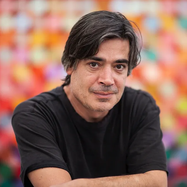 Portrait of Matthew Johnson in front of one of his multicoloured dot paintings